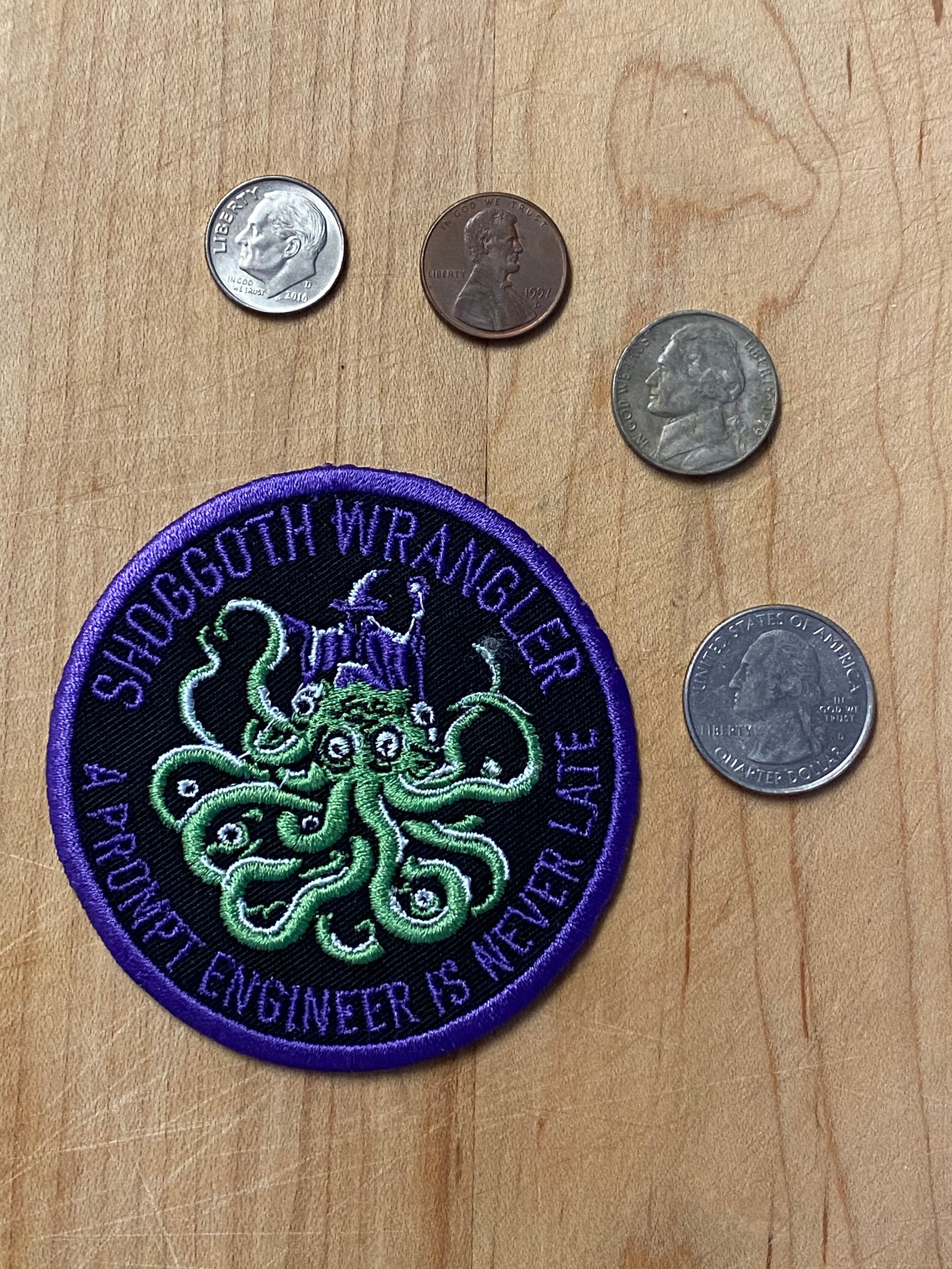 Actual photo of the Shoggoth Wrangler patch shown with US currency coins for scale